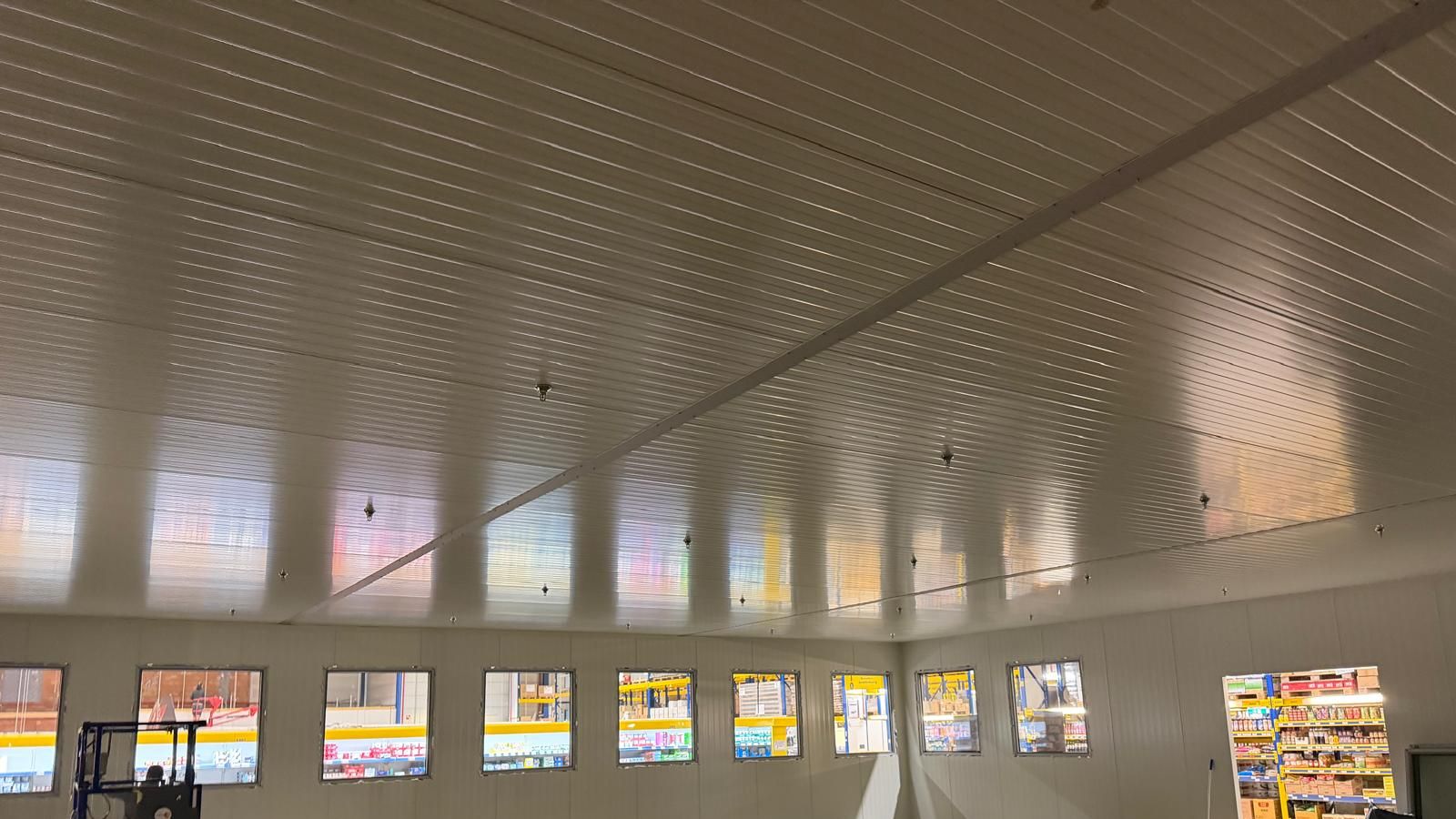 Innenansicht einer neuen Kühlhalle: weisse Deckenpaneele und eine Reihe von Sichtfenstern